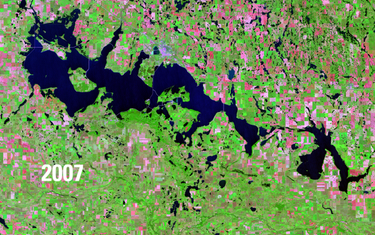Satellite image showing water bodies in deep blue, green vegetation and pink barren areas