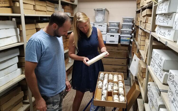 Two oceanographers look at a coral core stored in a wooden box