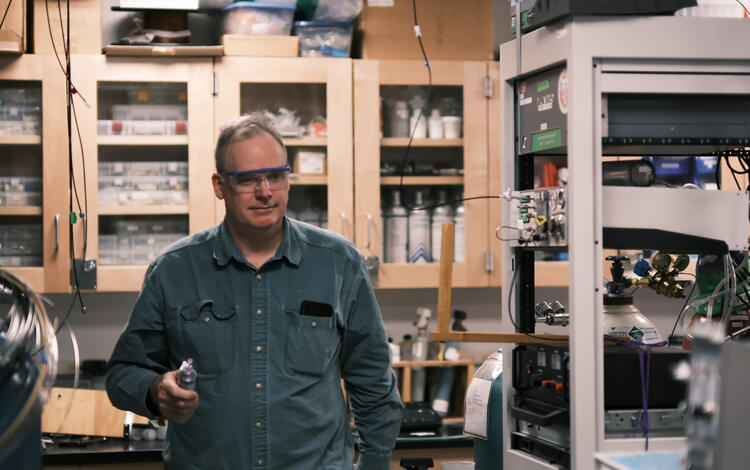Person holding object in hand walking through a laboratory