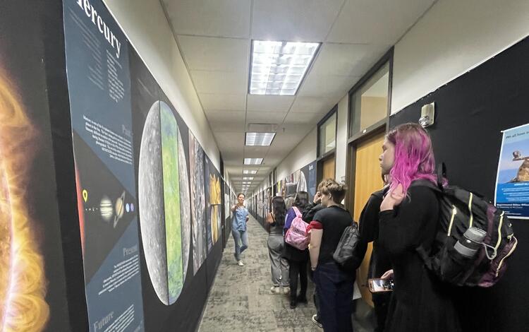 A USGS physical scientist speaks to students as they look at planetary posters in the Astrogeology building hallway 