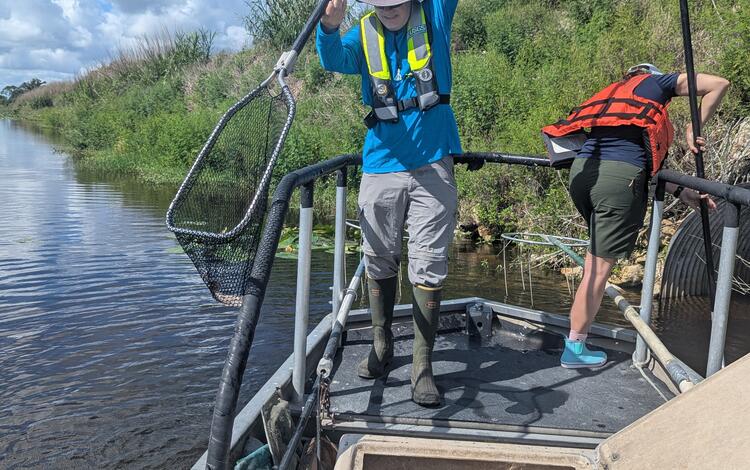 two people stand on a boat holding long nets
