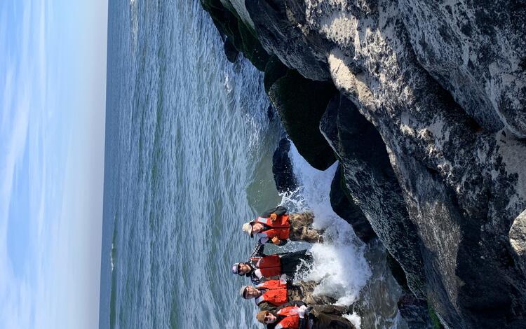 USGS Scientist standing in the surf along a rocky jetty