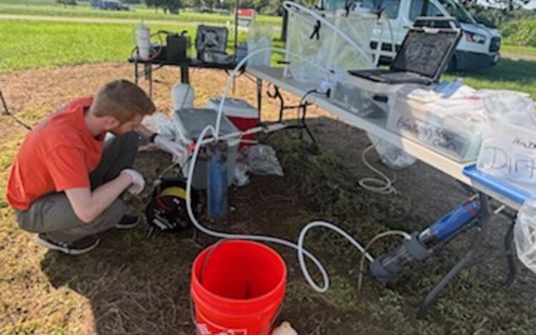 Scientist setting up sampling pump in well pipe.