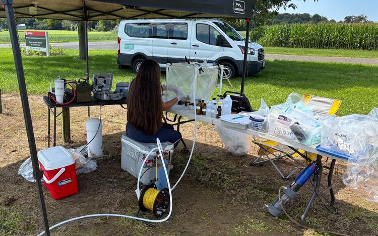 USGS Scientist collecting groundwater samples within a protective housing in the field