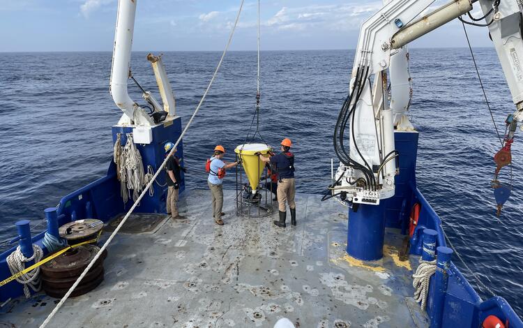 crew retrieving sediment sampler from ocean