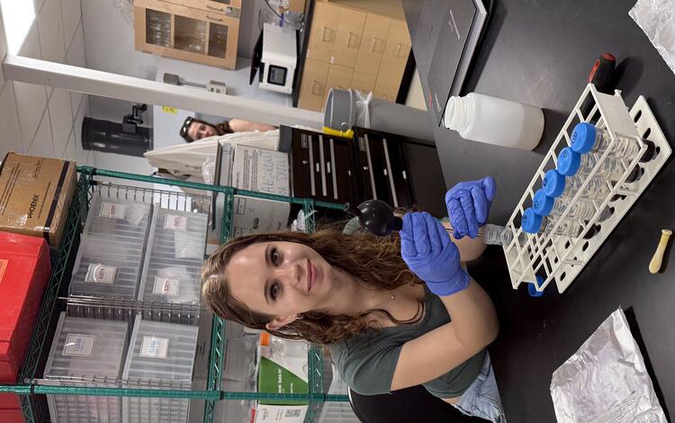 Intern working in a lab smiling to have her picture taken