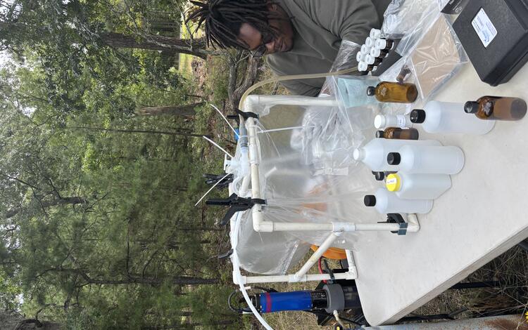 Scientist sitting at a field table working with samples inside a clean chamber