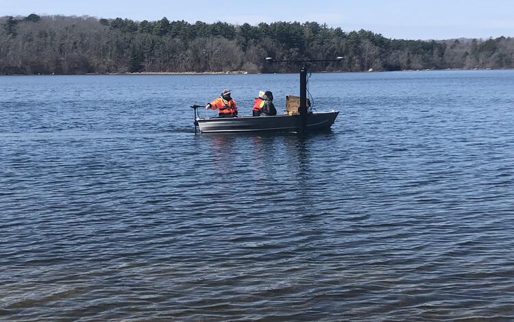 small boat on pond with trees in the background