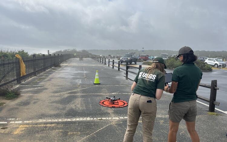 Two people in parking lot standing in front of drone