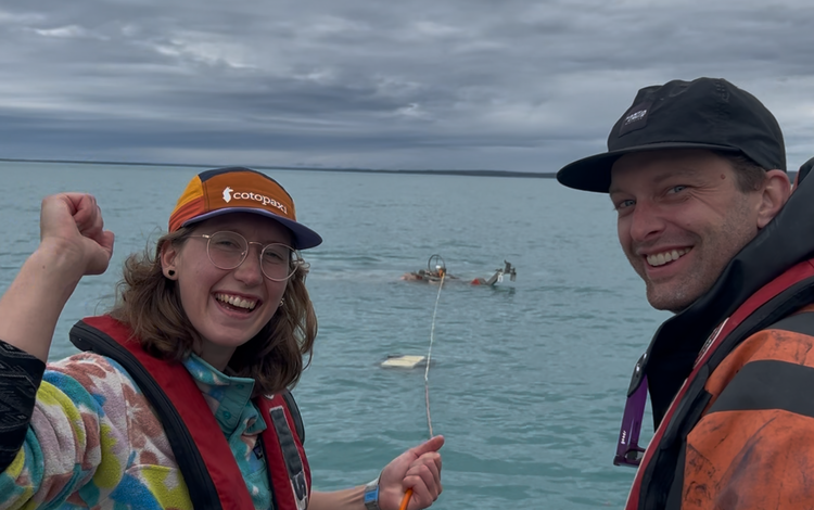 two people smiling, equipment in the water behind them