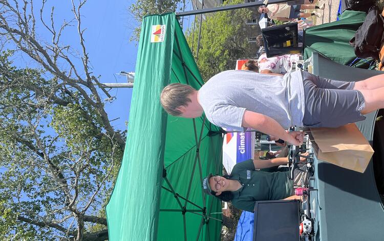 USGS scientist at booth outside with drones on it under tent outside talking to a person
