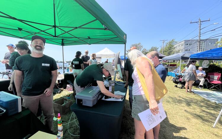 USGS scientists talking to visitors at booth under tent outside