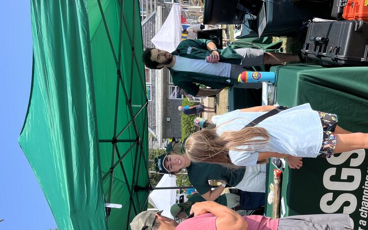 Man and child talking to USGS scientist at booth under tent outside
