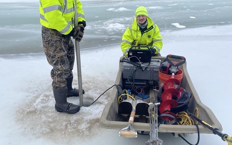 Scientists taking a reading of the flow under the ice on the river