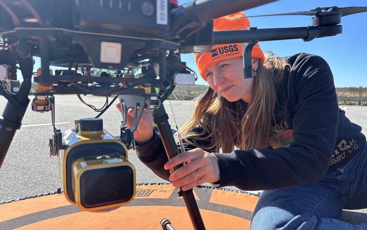 Jen kneeling down attaching a lidar mount to the bottom of a UAS