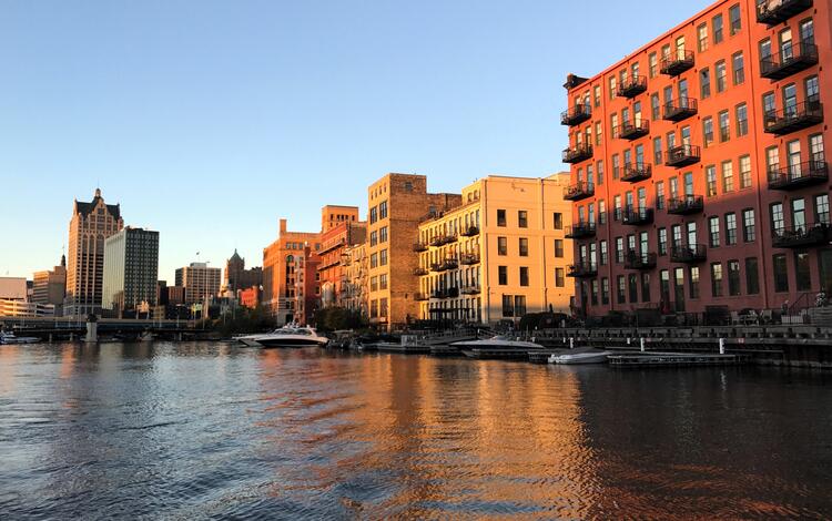 Sunset illuminating buildings in a city with a river in foreground