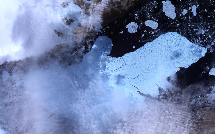 Satellite image of a glacier with chunks of ice in the water around the end of it