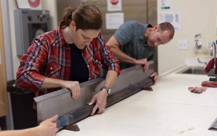 Scientists separating a sediment core split lengthwise