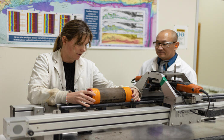 Scientists splitting a sediment core with the GeoTek core splitter