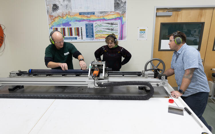 Scientists splitting a sediment core with the GeoTek core splitter