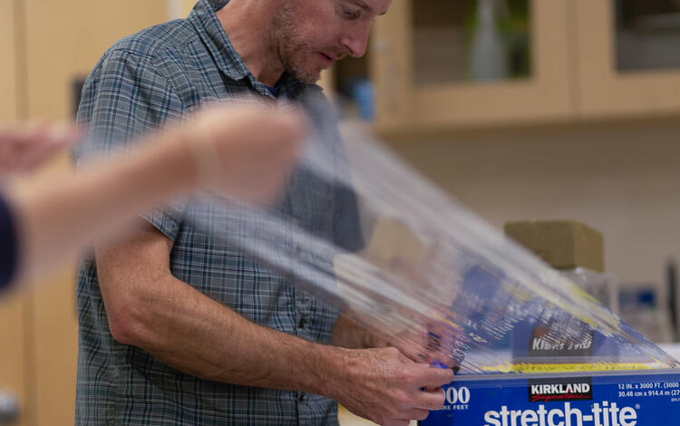 Scientists wrapping a split sediment core in plastic