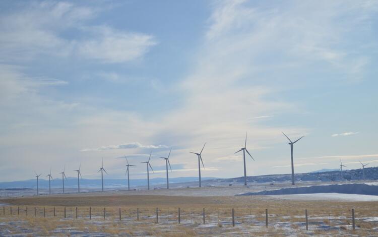 Row of wind turbines with a barb-wire fence in the foreground 