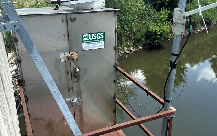 Streamgage housing on bridge on a summer day