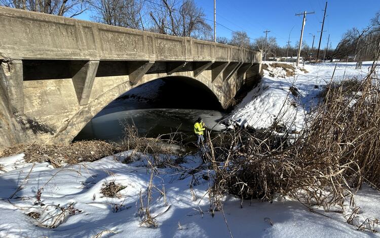 Scientists conducting discharge measurement in middle of stream during winter