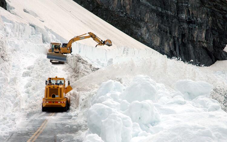 road crews with heavy equipment remove snow that was at least 20 feet deep