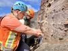 Color photograph of scientists sampling vertical exposure of explosive volcanic deposit